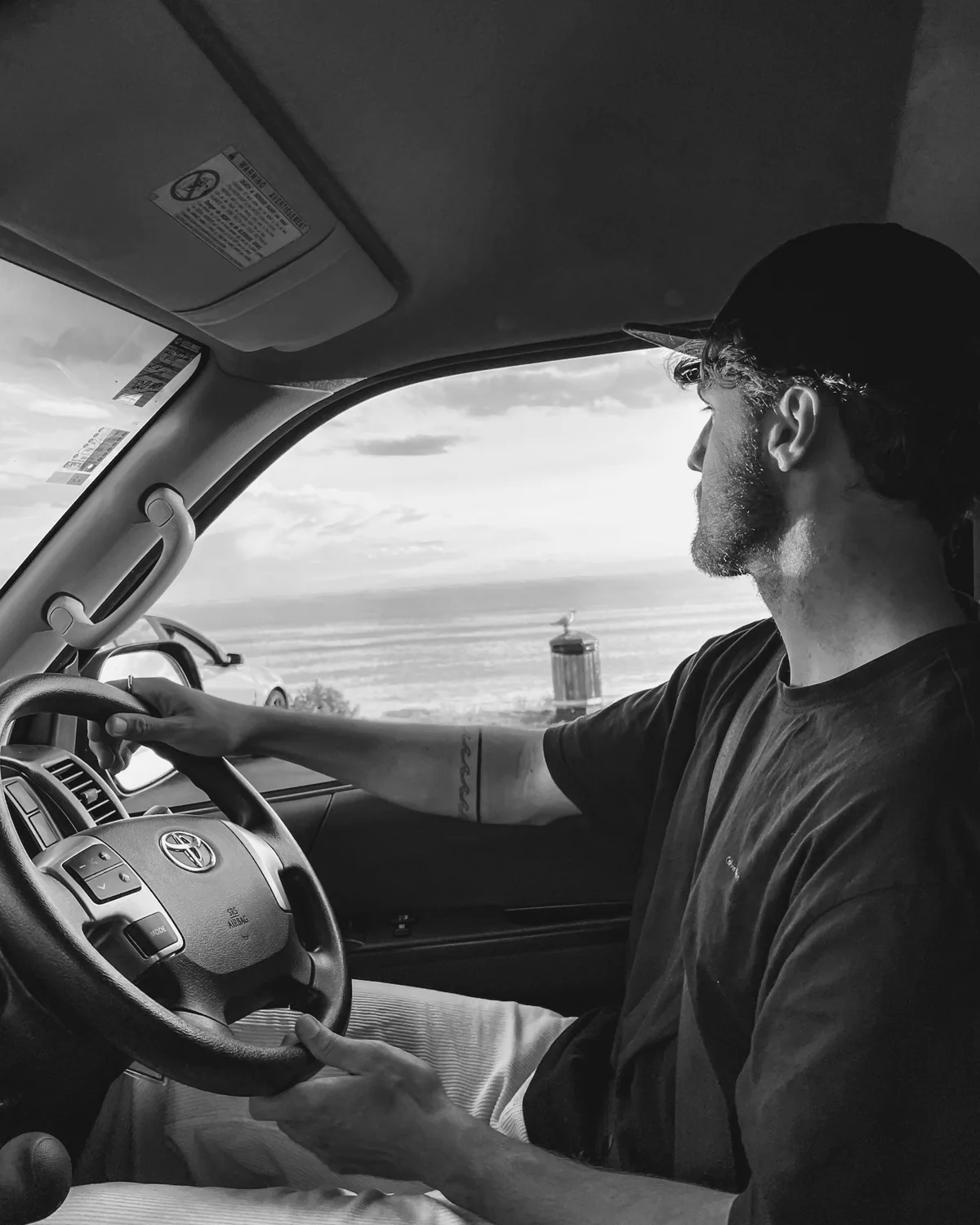 Motorista ao volante do próprio carro no fim da tarde